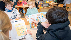 Kinder schauen sich Materialien aus dem Lernkoffer an