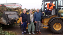 Ein Mann schaut aus dem Führerhaus eines Radladers, vor dem drei Erwachsene stehen.