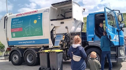 Ein junger Besucher darf im Führerhaus des großen Entsorgungsfahrzeugs Platz nehmen